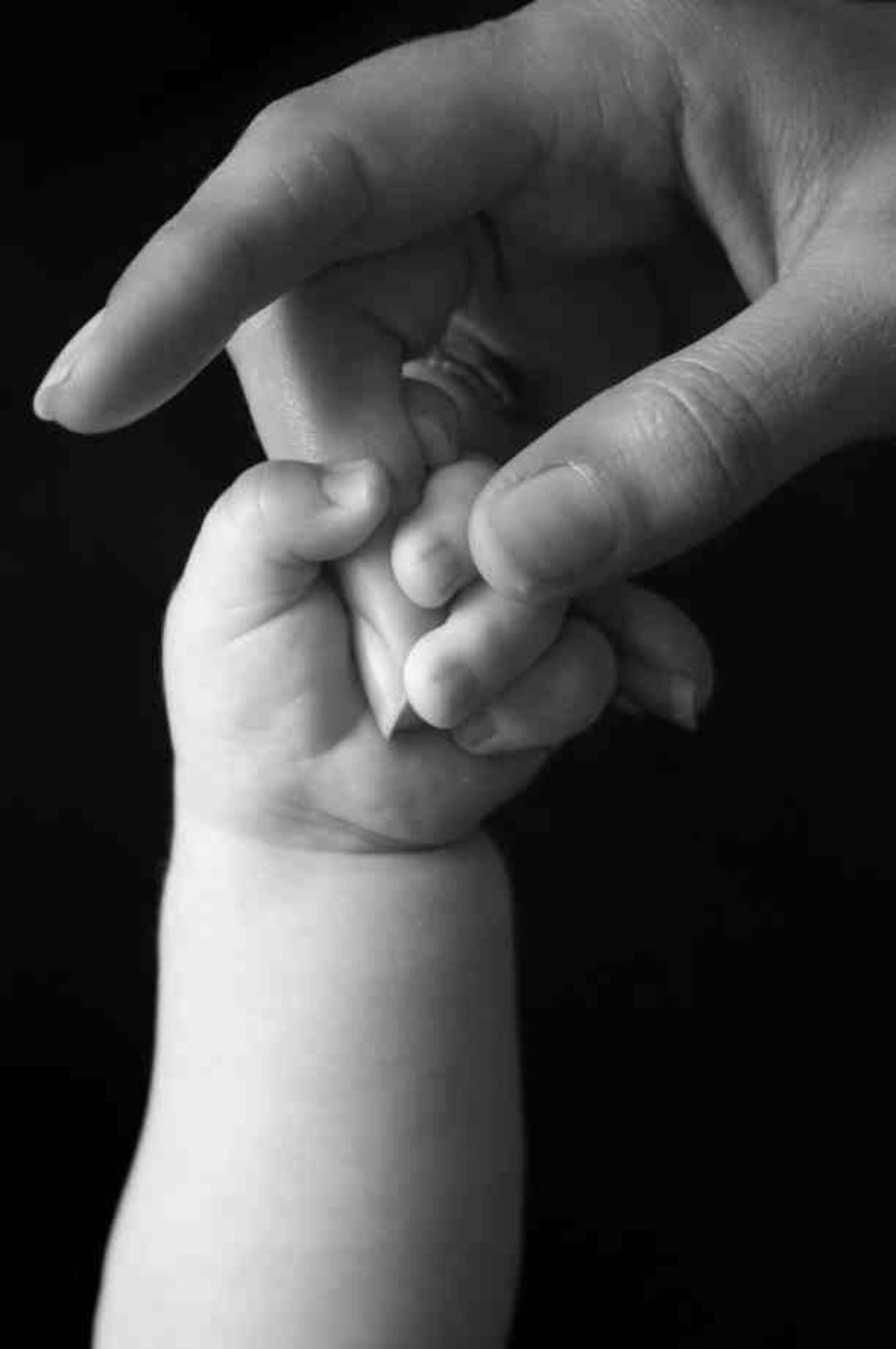 Baby hand gripping adult finger