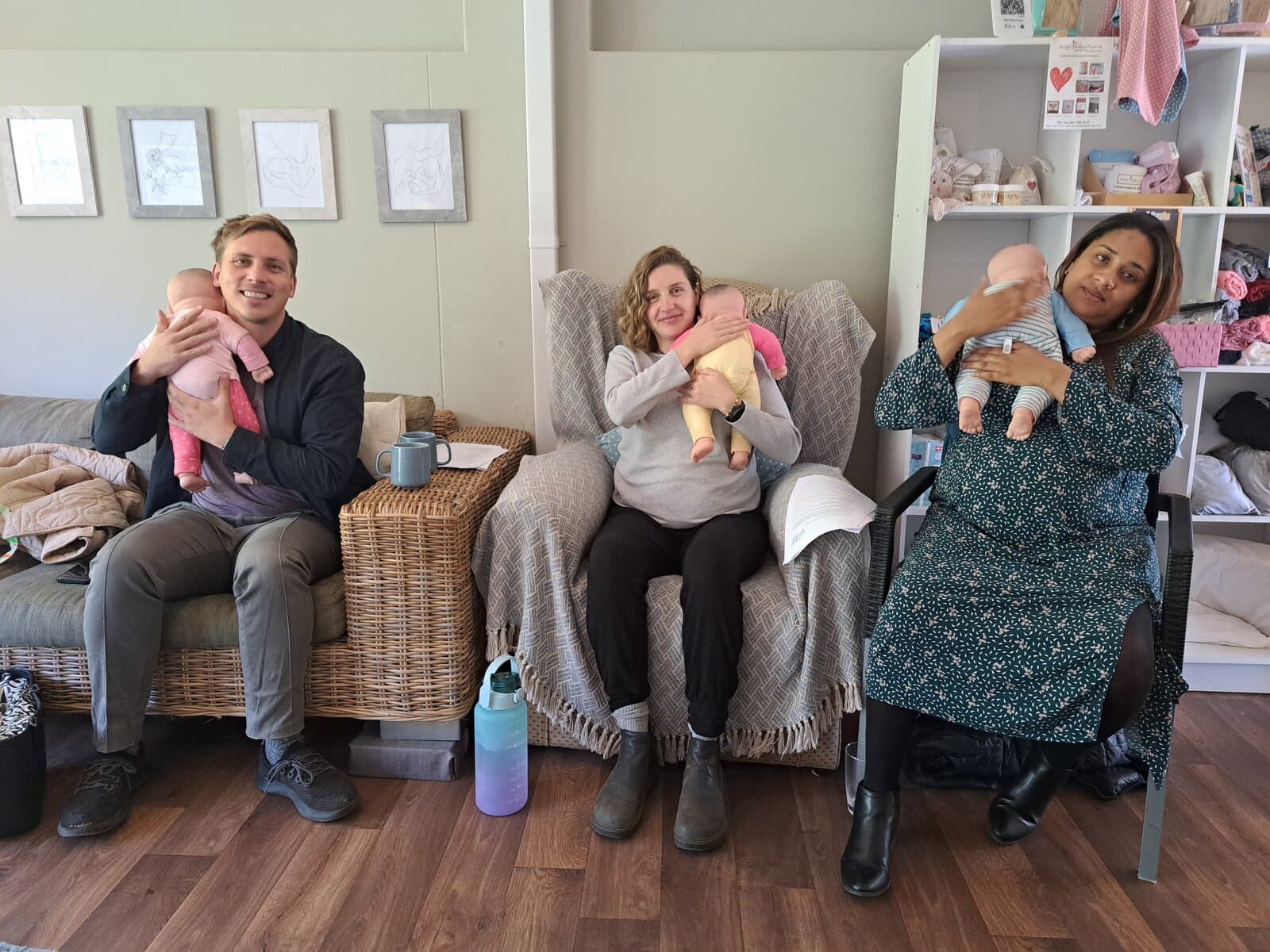 Three parents holding newborn babies at the clinic